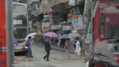 Verkehr-In-Hongkong-Während-Der-Hauptverkehrszeit-Mit-Fußgängern,-Die-Die-Kreuzung-überqueren,-Während-Busse-Vorbeifahren