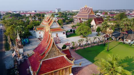 Traditionelle-Pagode-Mit-Gewölbtem-Dach-In-Der-Laotischen-Stadt-Savannakhet,-Drohnenflug-Bei-Abendlichem-Sonnenlicht