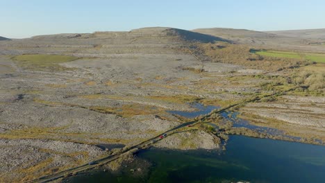 Dirt-road-cross-flooded-lake-plains-in-dramatic-limestone-karst-landscape-of-the-Burren-Ireland