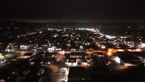 drone-flies-sideways-pan-across-small-town-cityscape-at-night-showing-lots-of-city-lights-while-cars-drive-on-the-roads