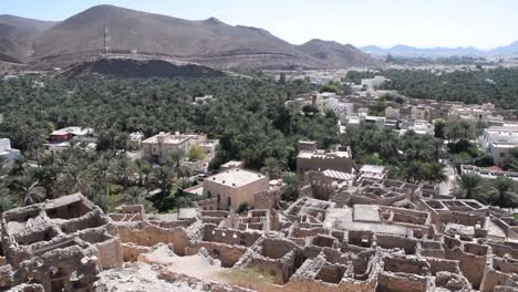 Casas-En-Ruinas-En-Birkat-Al-Mouz-En-Omán,-Con-Palmeras-Y-Montañas-Al-Fondo