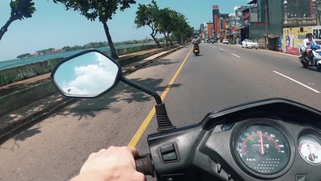 POV,-Close-up-of-man-driving-motorbike-on-tropical-island-during-beautiful-sunset-near-beach-while-traveling