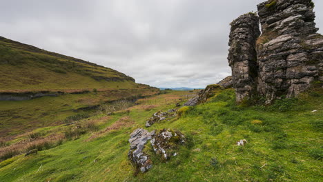 Panorama-motion-timelapse-of-rural-nature-farmland-with-boulder-rocks-in-the-foreground-grass-field-and-hills-in-a-valley-distance-during-cloudy-day-viewed-from-Carrowkeel-in-county-Sligo-in-Ireland