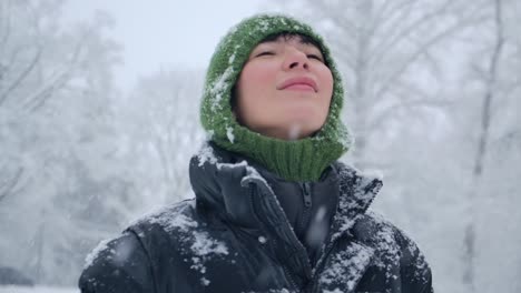 Enchanting-winter-scene-of-a-woman-enjoying-the-melting-snow-falling-from-the-trees,-slow-motion-footage