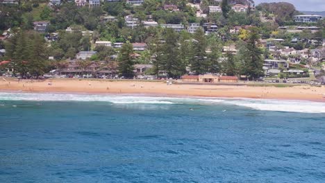 Aerial-reveal-of-surfers-bobbing-about-in-the-water-at-Palm-Beach-in-Sydney