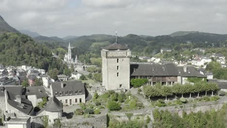 Chateau-fort-de-Lourdes-castle-perched-on-rock-with-Sanctuary-of-Notre-Dame-in-background,-Hautes-Pyrenees-in-France