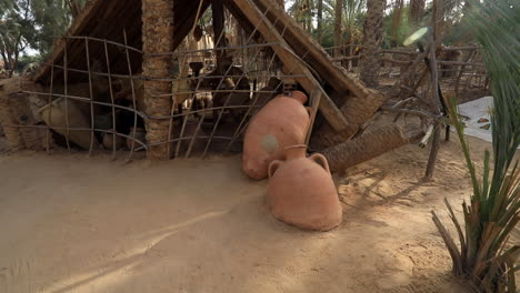 Traditional-African-huts-with-thatched-roofs-and-large-pottery-in-a-dusty-village-setting,-daytime