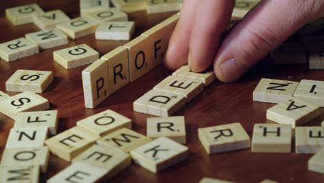 Word-DEBT-formed-with-Scrabble-letter-tiles,-PROFIT-word-knocked-over
