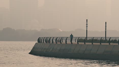 A-resident-taking-a-walk-during-a-misty-morning-at-Khalid-Lake-in-Sharjah,-United-Arab-Emirates