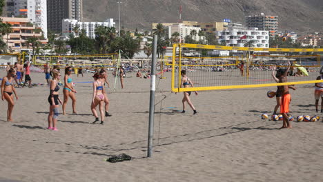 Beach-volleyball-training-in-full-swing,-with-players-diving-and-jumping-on-the-sandy-court-against-a-backdrop-of-palm-trees-and-urban-skyline