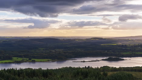 Zeitraffer-Der-Ländlichen-Landwirtschaftslandschaft-Mit-See,-Wald-Und-Hügeln-Während-Eines-Bewölkten-Abendsonnenuntergangs-Von-Oben-über-Lough-Meelagh-In-Der-Grafschaft-Roscommon-In-Irland