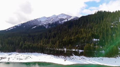 Forward-shot-of-Lake-Kachess-with-snow-bank-and-evergreen-forest-with-snowcapped-mountain