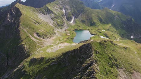 Serena-Vista-Aérea-Del-Lago-Capra-Ubicado-En-Las-Exuberantes-Montañas-Fagaras,-Rumania,-Bajo-Un-Cielo-Despejado