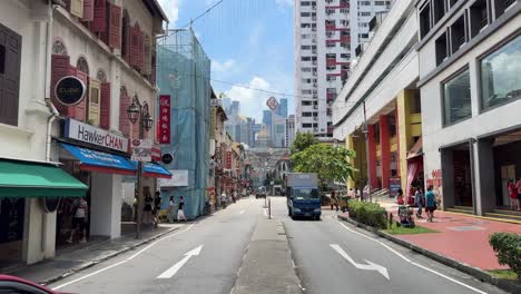 Street-scene-of-people-sauntering-and-vehicles-moving-slowly-in-Chinatown,-Smith-Street,-Singapore