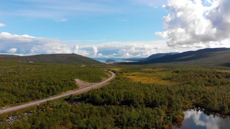 Aérea:-Carretera-Principal-En-El-Norte-De-Suecia-Entre-Bosques-Y-Lagos-Con-Muy-Poco-Tráfico-Y-Con-Un-Cielo-Azul-Y-Algunas-Nubes-Al-Fondo