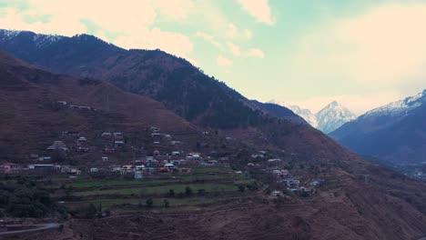 Vista-Aérea-De-La-Aldea-En-La-Ladera-De-Azad-Cachemira-Junto-A-Un-Río.