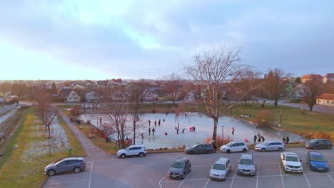 Scenic-Frozen-Lake-With-People-Ice-Skating-In-Winter---Drone-Shot