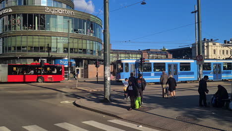 Public-Transportation-in-Central-Oslo,-Norway,-Buses,-Trams-and-People-on-Sunny-Day