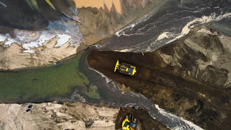 Vista-Estática-De-Arriba-Hacia-Abajo-De-Bulldozer-Y-Excavadora-Moviendo-Sedimentos-Y-Tierra-Para-Desviar-El-Canal-Del-Estanque