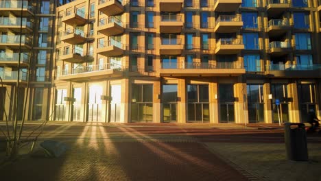 Sonnenlicht-Reflektiert-Im-Glas-In-Einem-Neuen,-Modernen-Wohngebäude-Am-Platz-Mit-Person-Und-Fahrrad