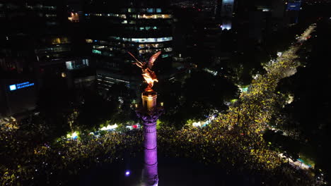 Aerial-view-orbiting-the-illuminated-El-Ángel-statue,-at-crowded-Reforma-Avenue