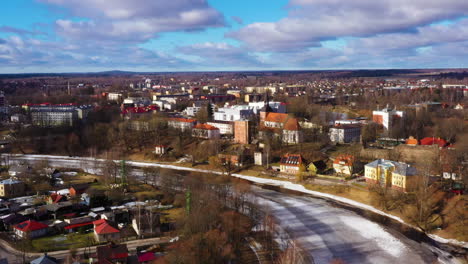 Aerial-footage-of-Valmiera-Latvia,-flying-over-River-Gauja-towards-shopping-mall-"Valleta"