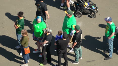 People-Wearing-Green-SELL-Shirts-At-Athletic-Fan-Fest-In-Oakland,-California