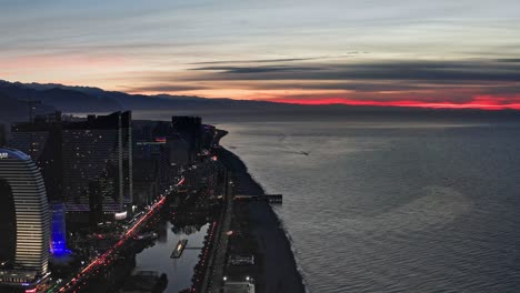 Black-sea-coastline-and-Batumi-evening-skyline-against-colorful-sunset-sky-at-dawn