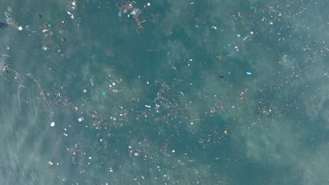 Von-Oben-Nach-Unten-Absteigende-Drohne-Geschossen-über-Verschmutztem-Wasser-Voller-Plastikmüll-Im-Türkisfarbenen-Tropischen-Wasser-Des-Balangan-Beach-In-Uluwatu,-Bali,-Indonesien