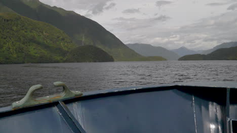 Slow-Motion-Pan-across-bow-of-a-boat-in-Doubtful-Sound-fjord-with-mountains-and-water---Patea,-New-Zealand