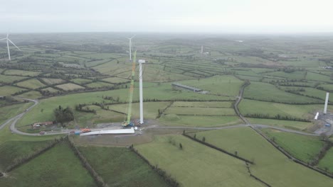 Wind-turbine-construction-in-rural-monaghan,-ireland,-with-lush-fields,-aerial-view