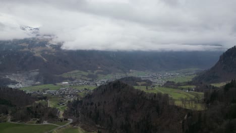 Aerial-establish-of-idyllic-european-countryside-rural-town-at-base-of-mountains-covered-by-clouds