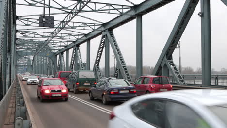 Traffic-driving-across-Vistula-River-on-truss-bridge,-Torun,-Poland,-slow-motion