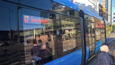 Öffentliche-Verkehrsmittel-Im-Zentrum-Von-Oslo,-Norwegen,-Straßenbahn,-Die-An-Einem-Sonnigen-Tag-An-Der-Kreuzung-Zwischen-Gebäuden-Im-Stadtzentrum-Vorbeifährt