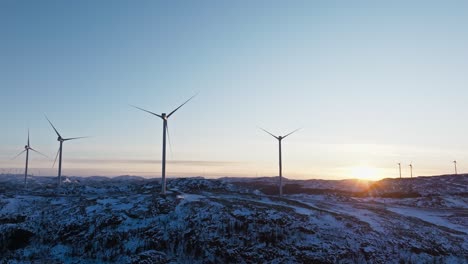 Windmills-In-Snowy-Mountains-Of-Bessaker,-Norway-At-Sunset---Drone-Shot