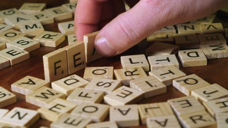 Auf-Der-Tischplatte-Formt-Die-Hand-Das-Wort-„Angst“-In-Scrabble-Buchstabensteinen,-Nahaufnahme