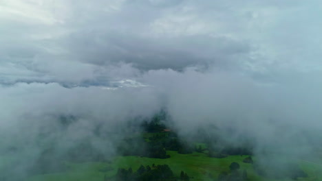 Rural-area-covered-in-thick-fog,-aerial-view-from-above-low-clouds-in-the-dawn