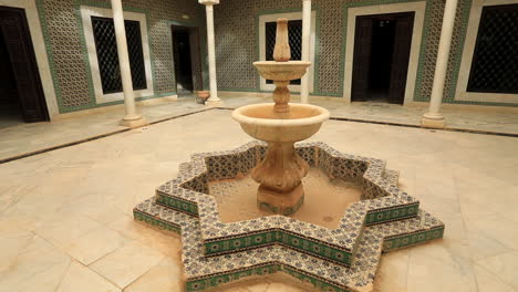 Courtyard-of-an-Arabic-house-with-ornate-fountain-in-Sbeitla,-sunlit-and-tranquil