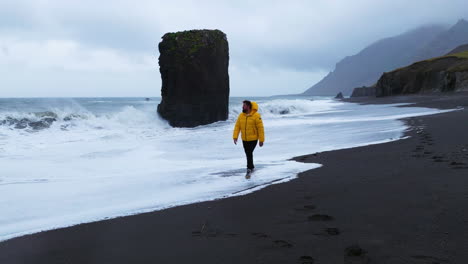 Man-Walks-In-The-Coastline-Of-Laekjavik-Beach-With-Foamy-Waves-In-Iceland