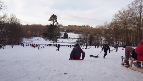 People-Enjoying-Snow-Sledding-At-Woluwe-Park-In-Woluwe-Saint-Pierre,-Belgium