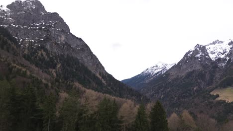 Drone-rise-up-to-summit-cross-towards-snow-covered-mountains-surrounded-with-pine-forest-in-Austria