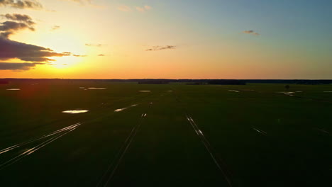 Aerial-drone-shot-over-train-tracks-passing-along-barren-plains-with-sun-setting-in-the-background