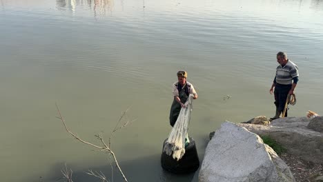 Ein-Einheimischer-Fischer-Im-Nahen-Osten-Fischt-Allein-Mit-Handgefertigten-Netzen-Auf-Einer-Steinplattform-Am-Strand,-Traditionelle-Fertigkeit,-Im-Strandkaukasus-Im-Hafen-Frische-Meeresfrüchte-Aus-Dem-Meer-Zu-Fangen