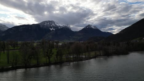 Aerial-parallax-around-shoreline-with-stunning-Swiss-mountains-and-epid-clouds-in-distance