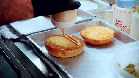 Imágenes-Cinematográficas-De-Cocina-De-Comida-De-4k-De-Un-Chef-Preparando-Y-Haciendo-Una-Deliciosa-Hamburguesa-Casera-En-La-Cocina-De-Un-Restaurante-En-Cámara-Lenta-Poniendo-Salsa-En-Los-Panecillos