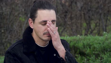 Portrait-of-a-young,-sad-and-tired-man-wearing-a-black-jacket-and-glasses