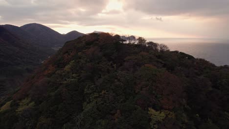 Aerial-sunshine-sunset-landscape-on-mountain-top-of-Kyotango-Kyoto-surreal-Japan-beach-travel-destination,-godlike-forested-hills,-establishing-shot-at-sea-coastline