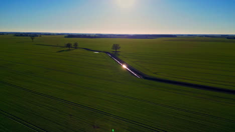 Wassergraben,-Umgeben-Von-Endlosen-Grünen-Landwirtschaftlichen-Feldern,-Drohnenansicht-Aus-Der-Luft