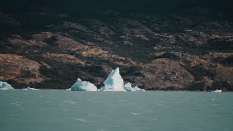 Icebergs-In-Argentino-Lake-Against-The-Mountain-Seen-From-A-Sailing-Boat