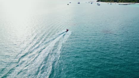 Jet-ski-races-across-stunning-crystal-shimmering-water-of-Fulidhoo-island-Maldives,-aerial-tracking